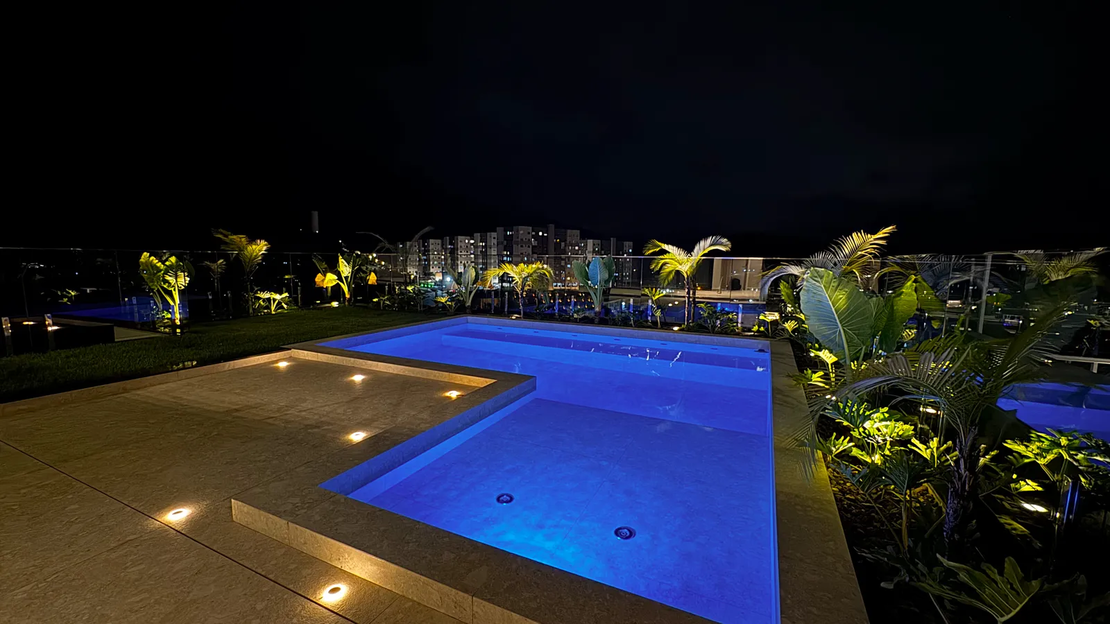 Piscina iluminada da Casa Van Gogh à noite, com as luzes da cidade ao fundo