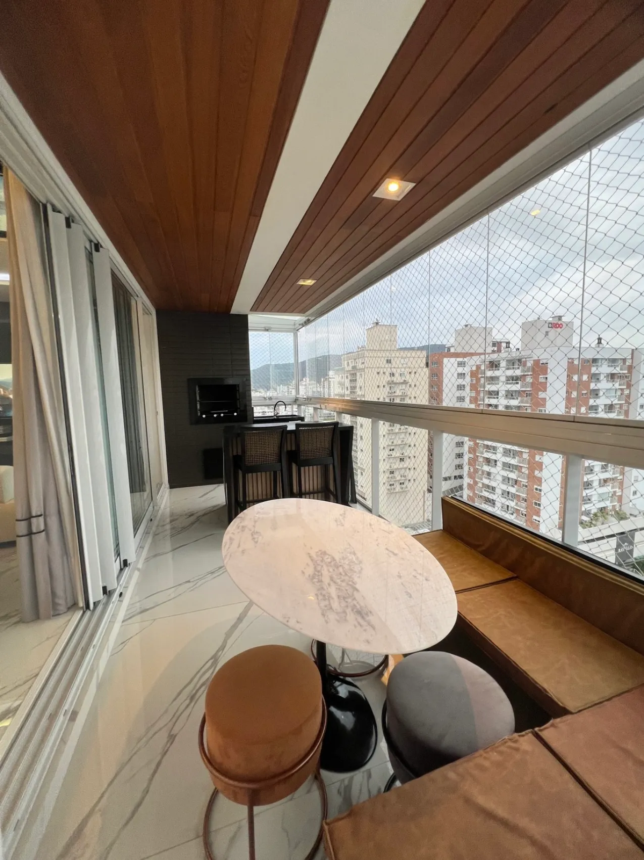 Varanda gourmet integrada, com forro de madeira e vista para a cidade